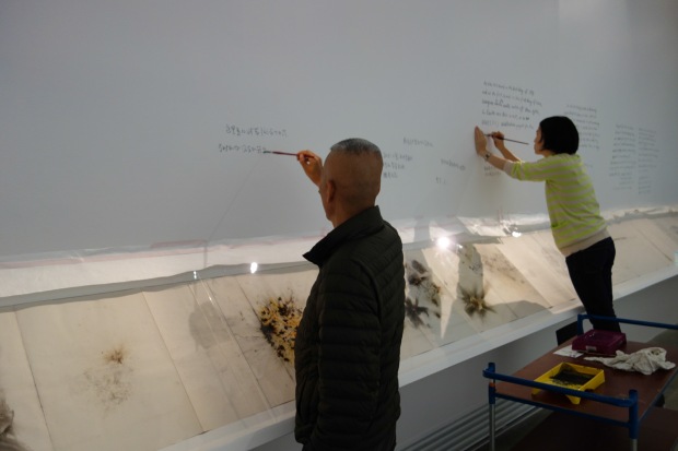 Cai Guo-Qiang and project director, Chinyan Wong, writing on the wall during installation process of Cai and Hong Hong at Fondation Cartier, 1993,  Paris, France, 2014 Photo by Mariluz Hoyos, courtesy of Cai Studio